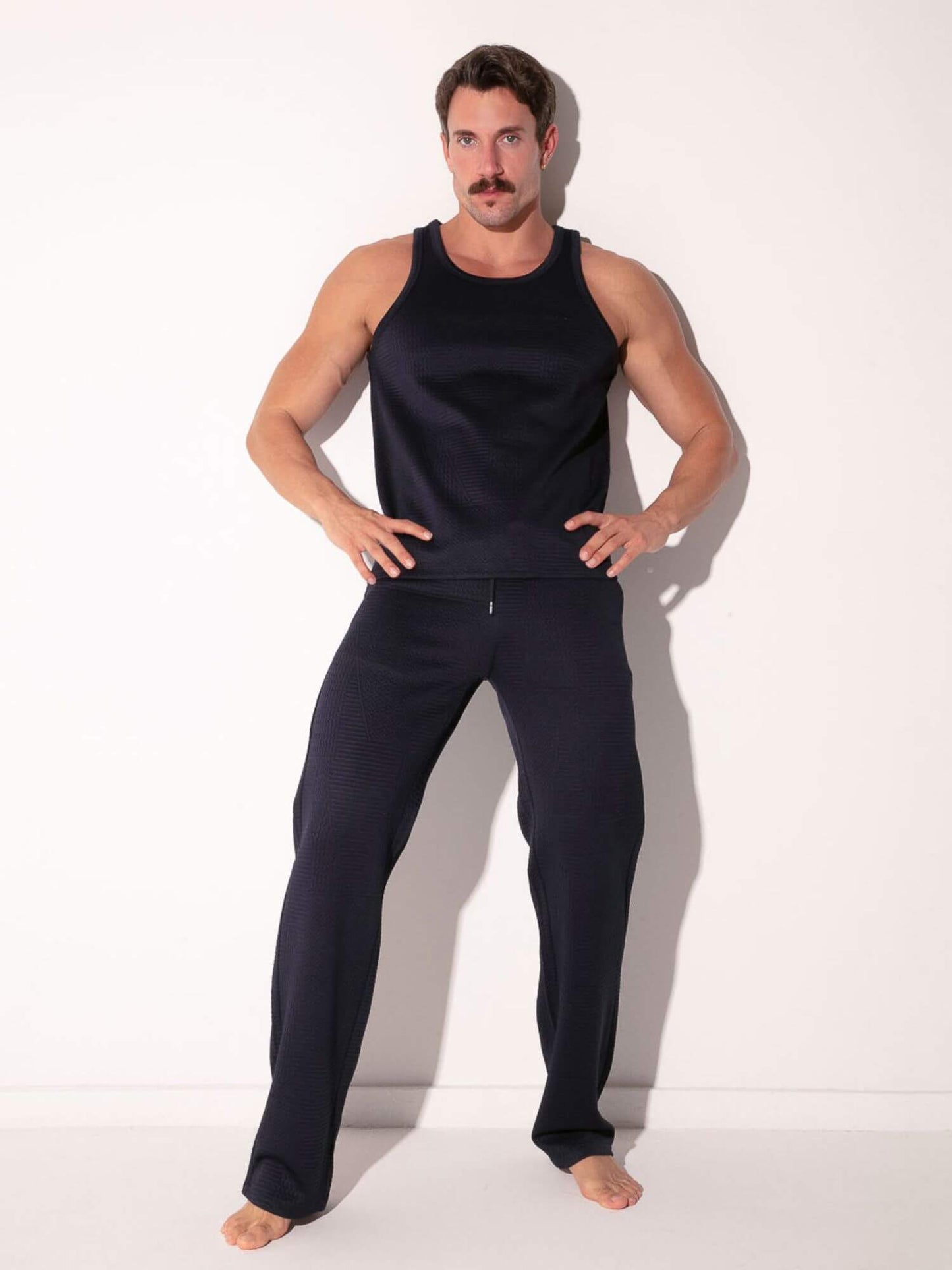 Man wearing a CODE 22 Medley navy tank top and pants on a white background