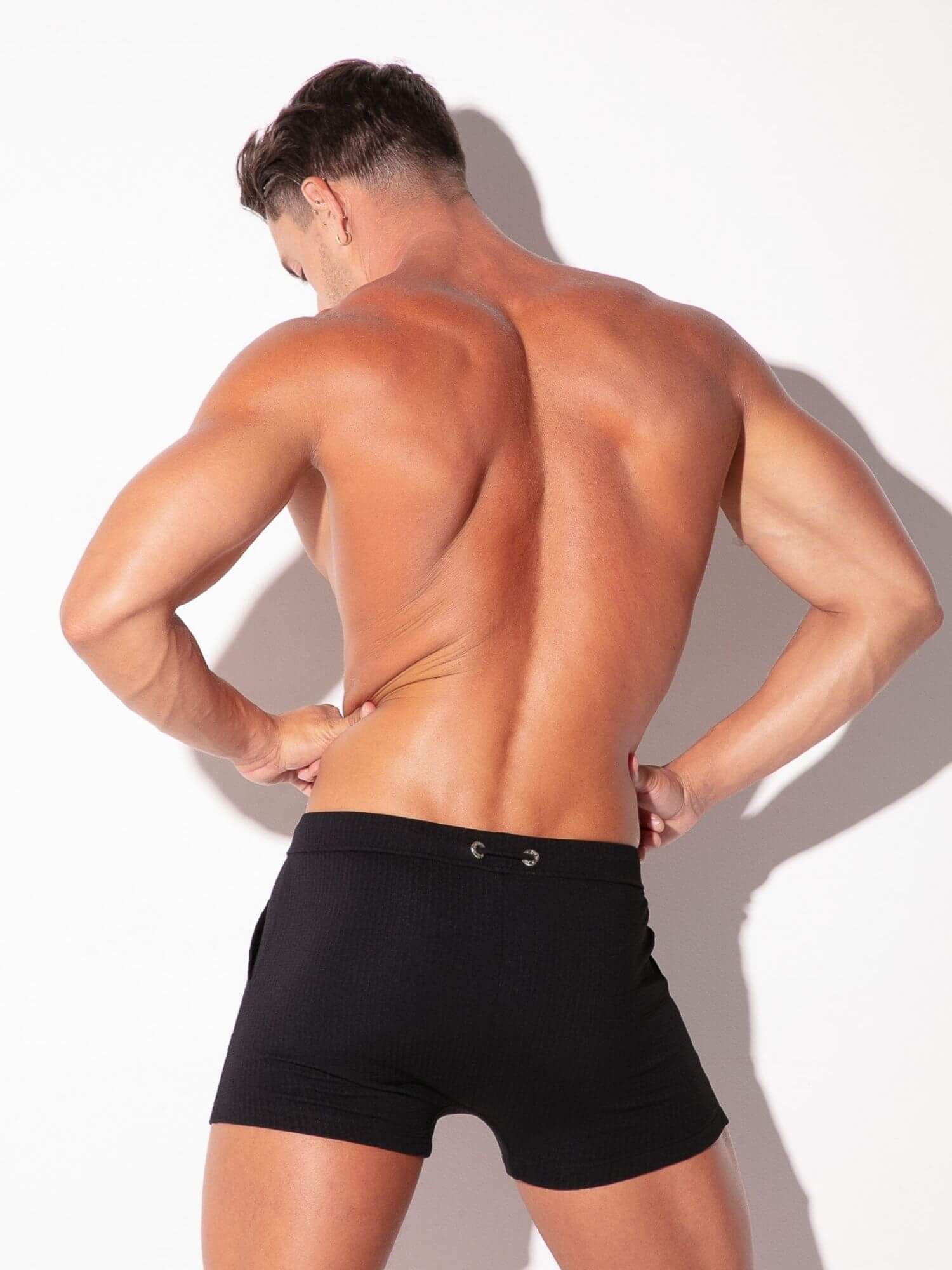 Man wearing black swimwear against a white background
