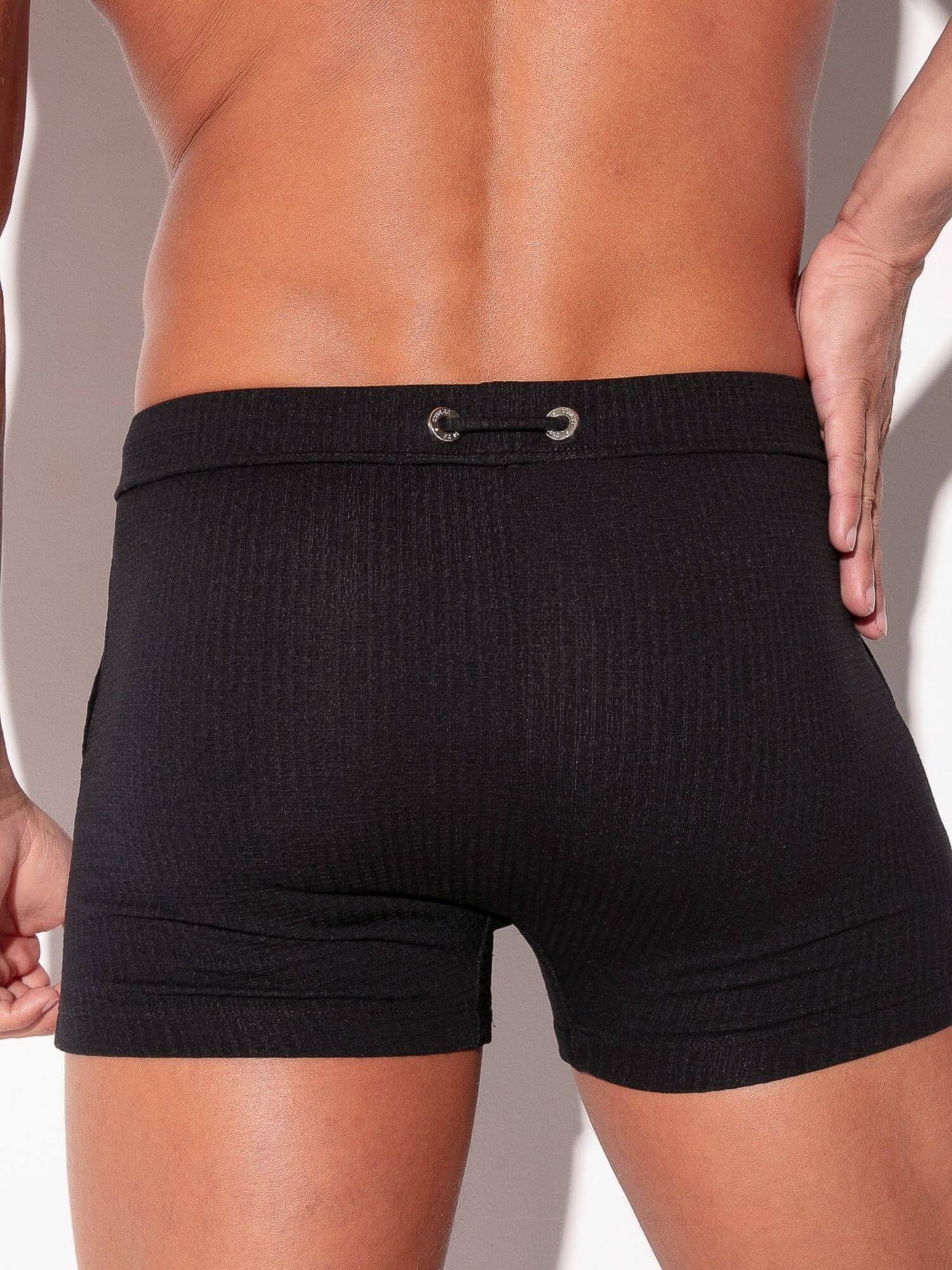 Black swimwear worn by a person on a neutral background