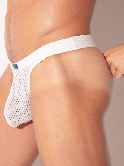 White mesh thong worn by a person on a beige background