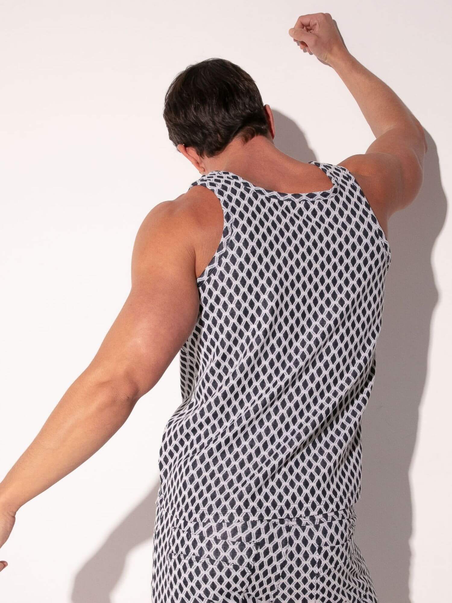 Man wearing a black and white patterned tank top against a white background