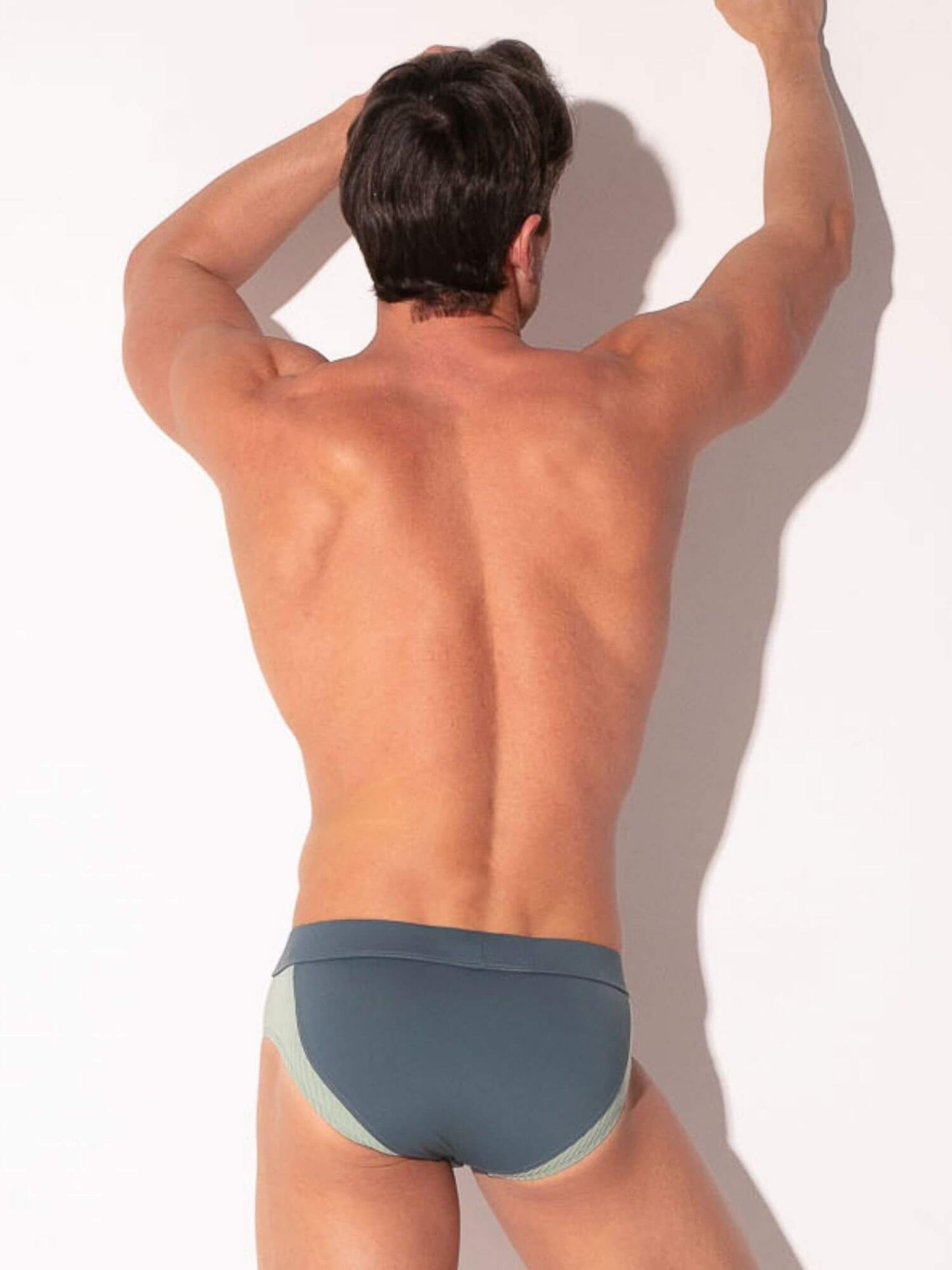Man wearing grey swim brief against a white background