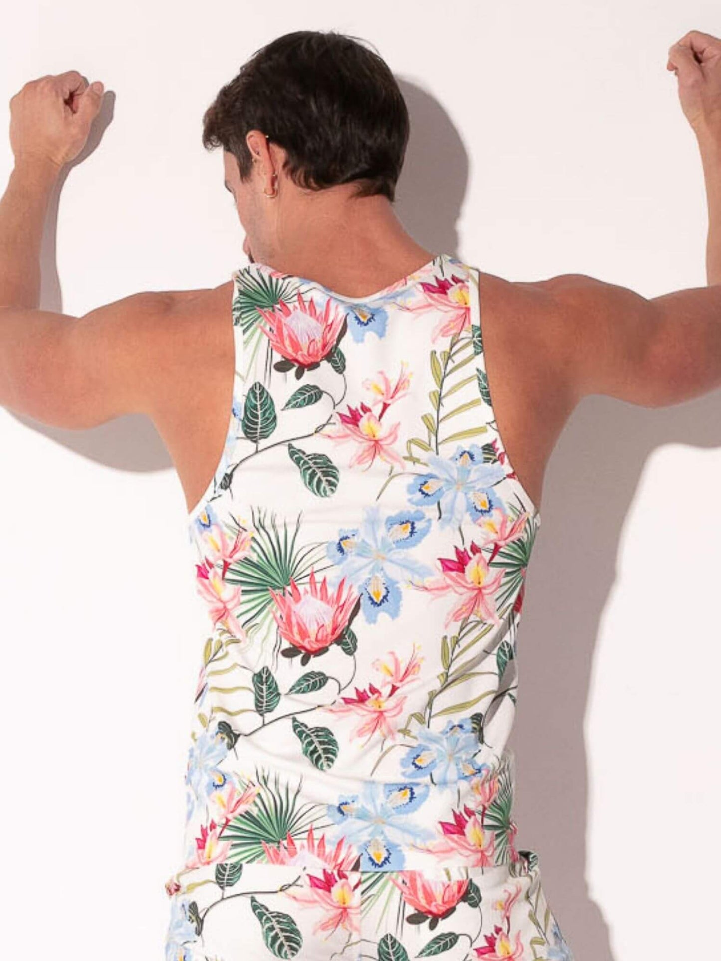 Person wearing a colorful floral tank top against a plain background