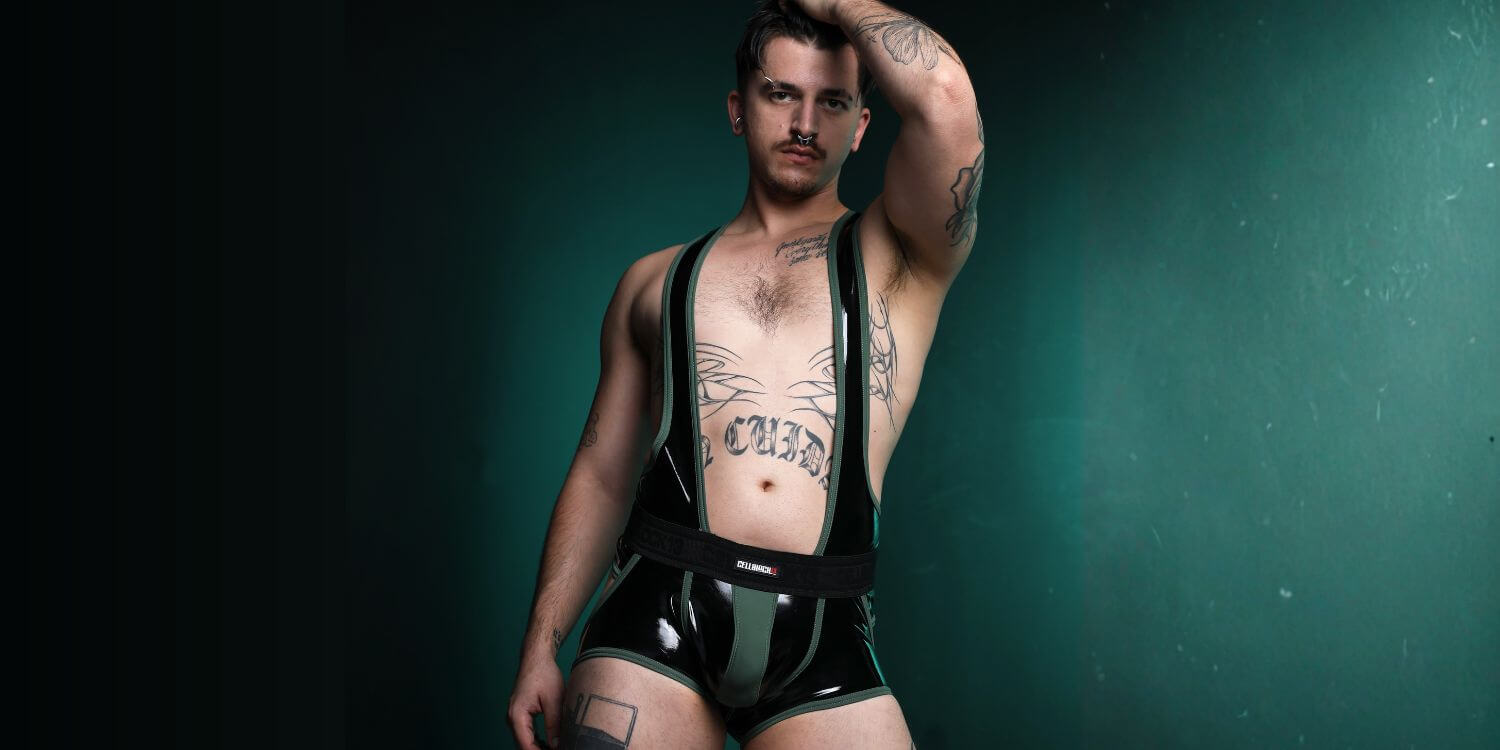 Man wearing a CellBlock 13 black latex look outfit against a dark green background
