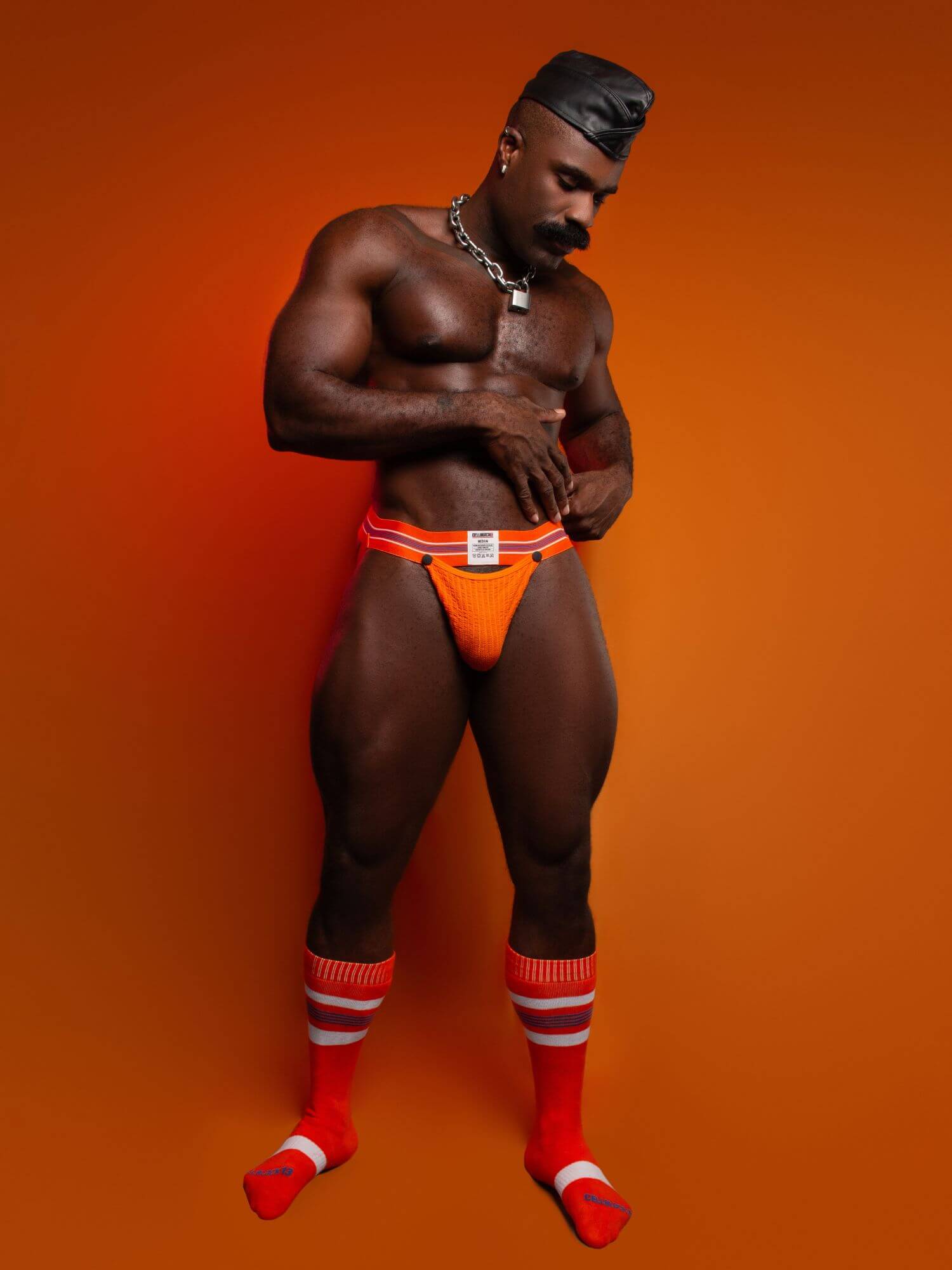 Person wearing orange underwear and red socks against an orange background