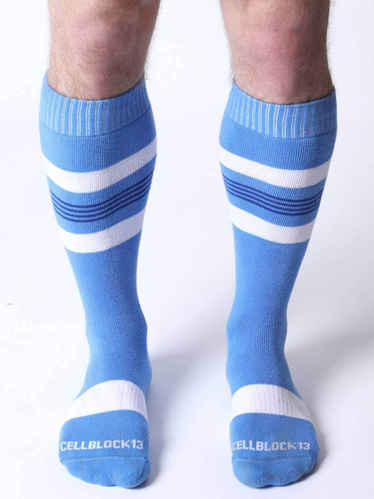 Blue knee-high socks with white stripes worn by a person on a white background