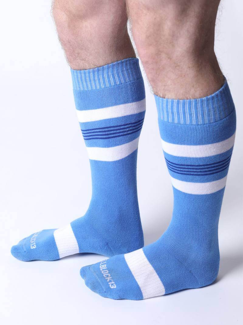 Blue knee-high socks with white stripes worn by a person on a white background