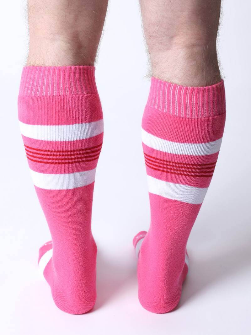 Pink knee-high socks with white stripes worn by a person on a white background