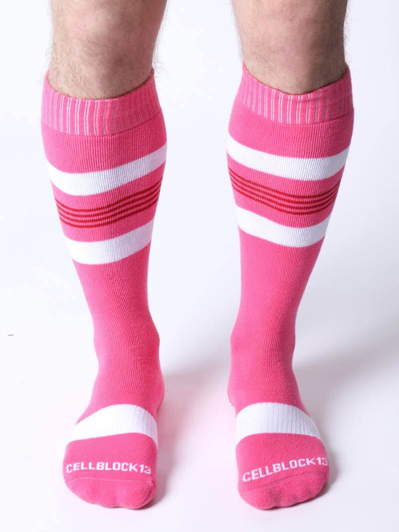 Pink knee-high socks with white stripes worn by a person on a white background