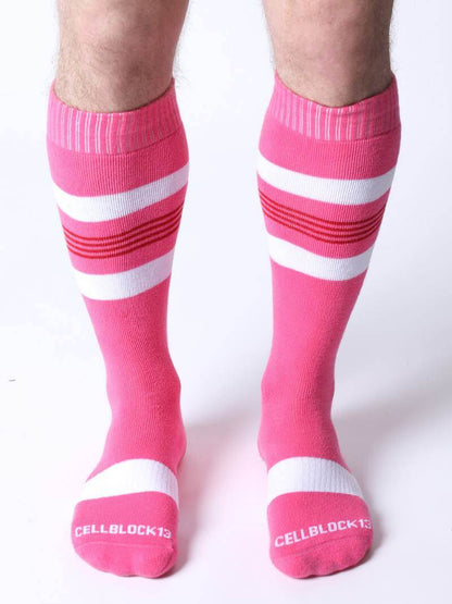 Pink knee-high socks with white stripes worn by a person on a white background