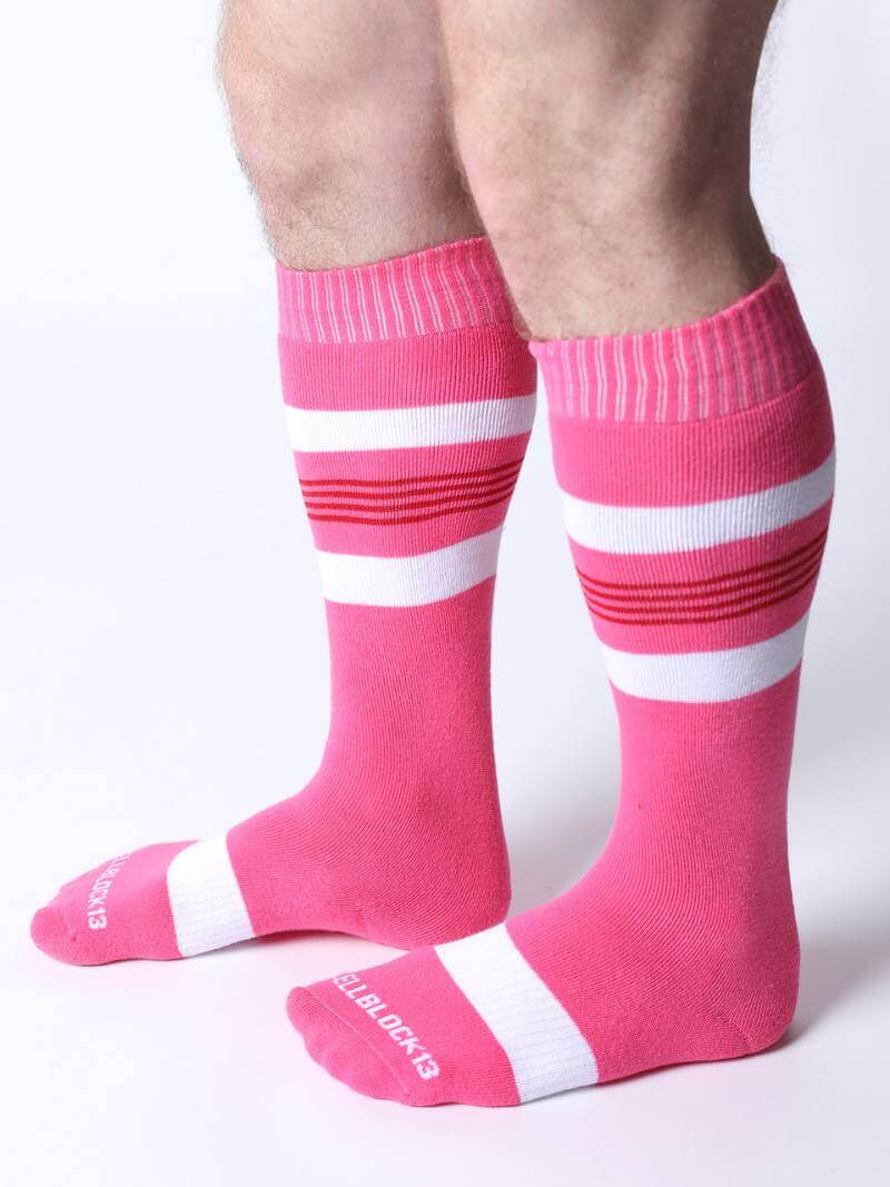 Pink socks with white stripes worn by a person on a white background