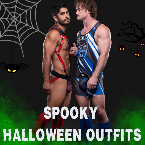 Two men in Halloween-themed outfits with a spider web and pumpkins in the background.