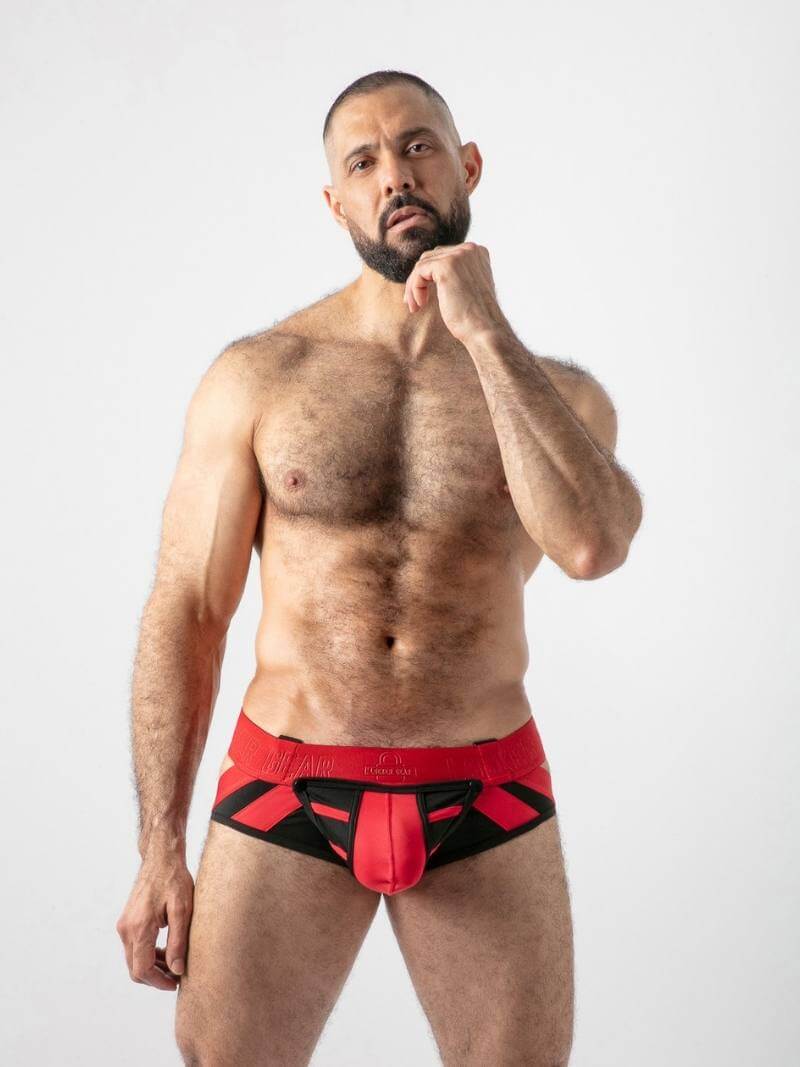 Man wearing red and black swim briefs on a white background
