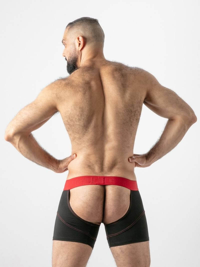 Man wearing black boxer briefs with red waistband on a plain background