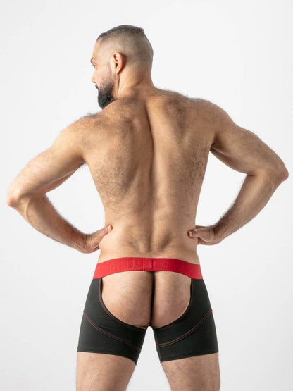 Man wearing black boxer briefs with red waistband on a plain background