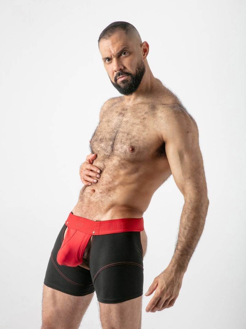 Man wearing black boxer briefs with a red waistband on a white background