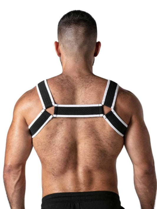 A man viewed from behind wearing a black and white posture corrector harness on his upper back and shoulders, set against a plain white background.