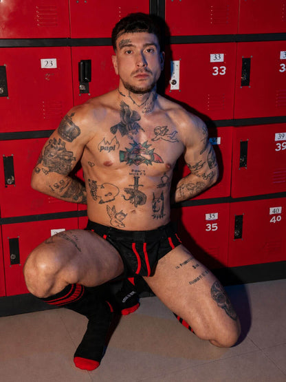 Man with tattoos posing in front of red lockers