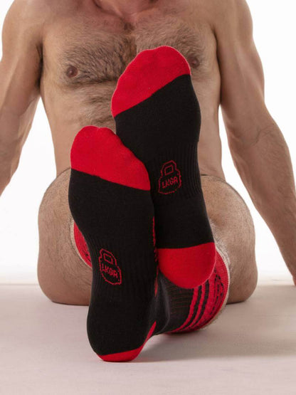 Black and red socks with a visible brand logo worn by a person on a neutral background