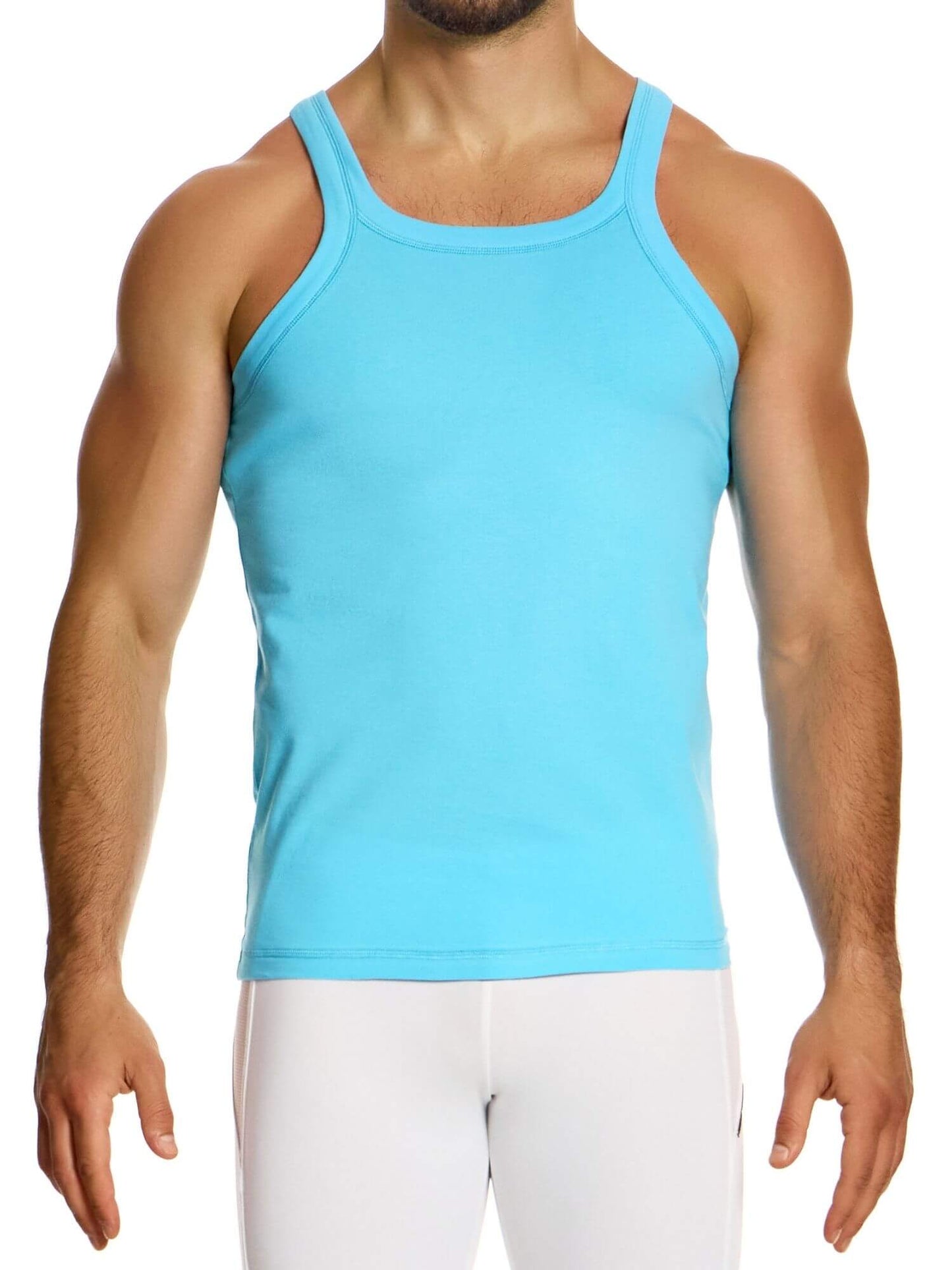Man wearing a light blue tank top and white pants on a white background