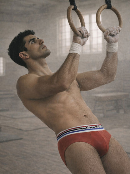 Man performing a pull-up on rings with a blurred gym background