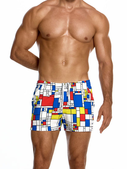 Man wearing colorful geometric patterned swim shorts on a white background
