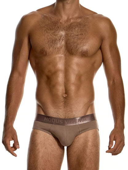 A male model wearing a pair of low-rise briefs in taupe brown, featuring a wide elastic waistband with the brand name 'MODUS VIVENDI' printed in white. The photo is shot against a clean white background.