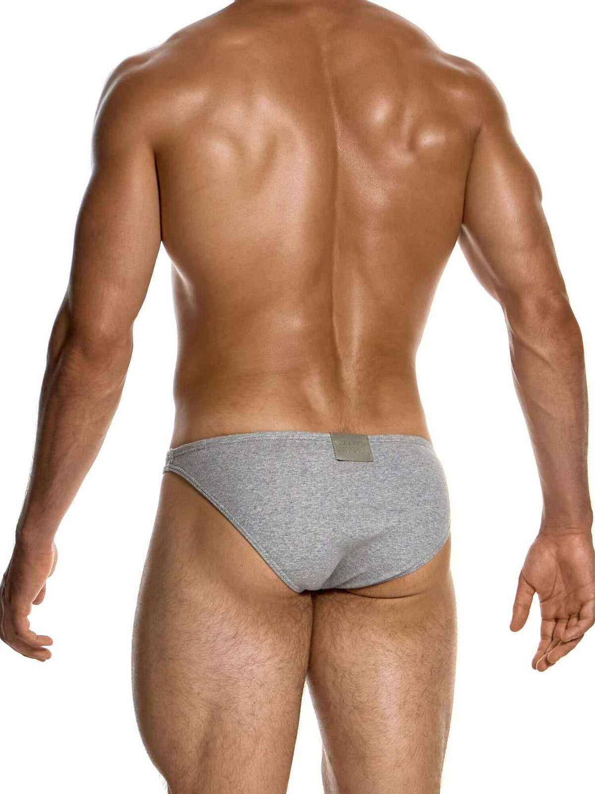 Rear view of a muscular man wearing heather gray briefs against a plain white background.