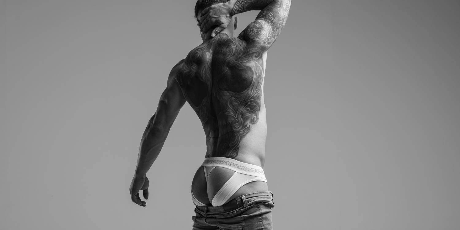 Man wearing a white thong against a gray background
