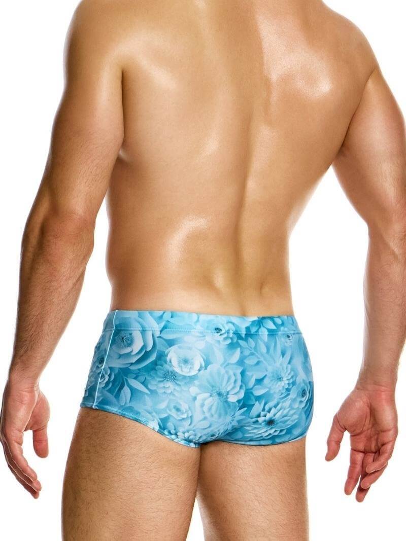Man wearing blue swim briefs with floral pattern on a white background