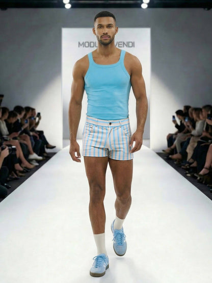 Model walking on a runway wearing a light blue tank top and striped shorts.
