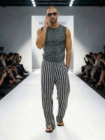 Model walking on a fashion show runway wearing a sleeveless patterned top and striped pants.