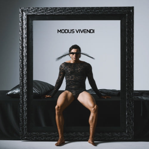 Person wearing a black textured garment inside a large black frame with 'Modus Vivendi' text.