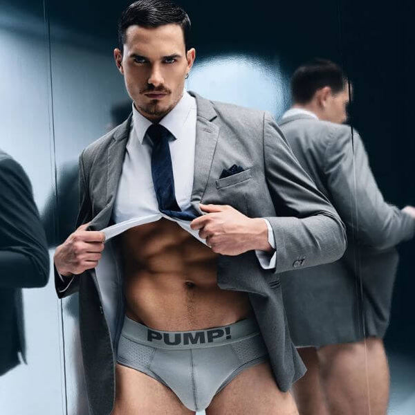 Man in a suit with his jacket open, revealing PUMP! Mr Gray underwear with 'PUMP!' branding.