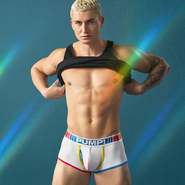 Man wearing colorful PUMP! Spectrum underwear with 'PUMP!' branding against a blue background