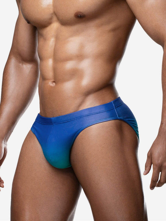 Man wearing a blue swim brief against a neutral background
