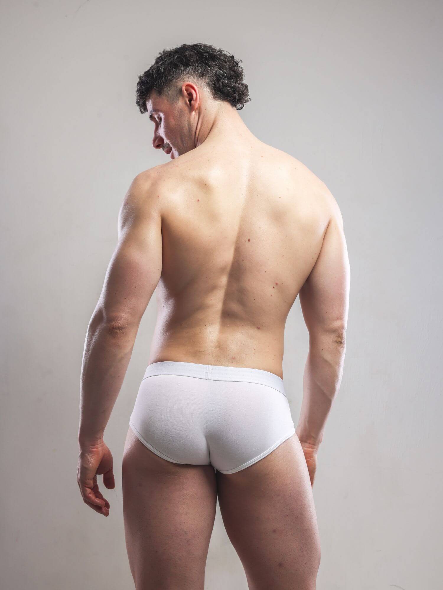 Man wearing white underwear against a plain background