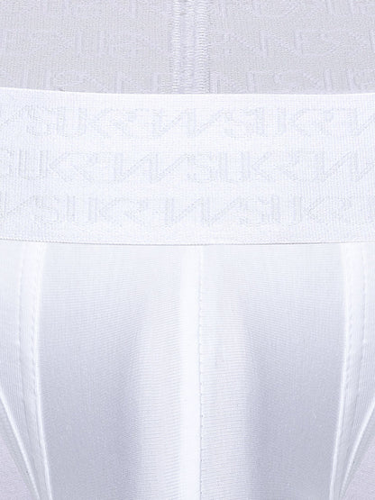 Close-up of a white underwear or garment waistband with a repeating tonal SUKREW logo pattern, shown against matching white fabric.