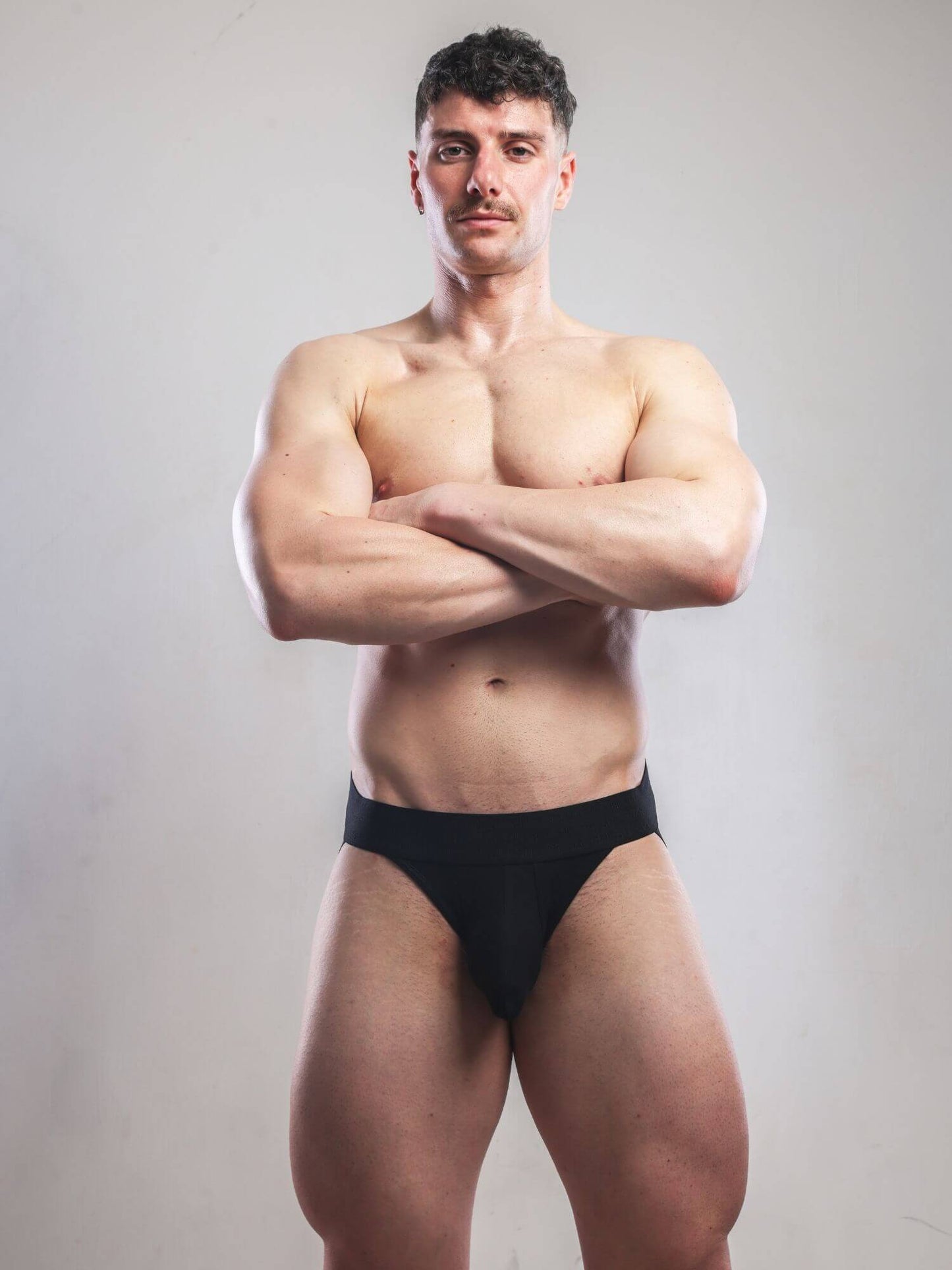 Man wearing black underwear against a plain background