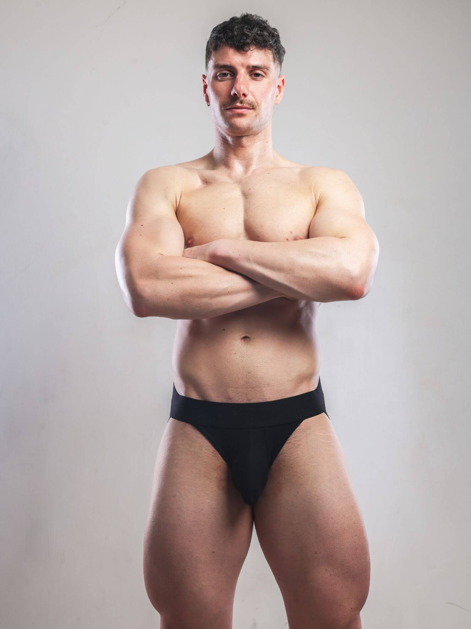 Man wearing black underwear against a plain background