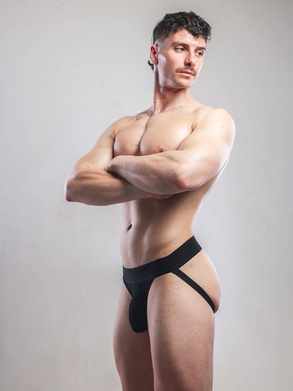 Man wearing a black jockstrap against a plain background