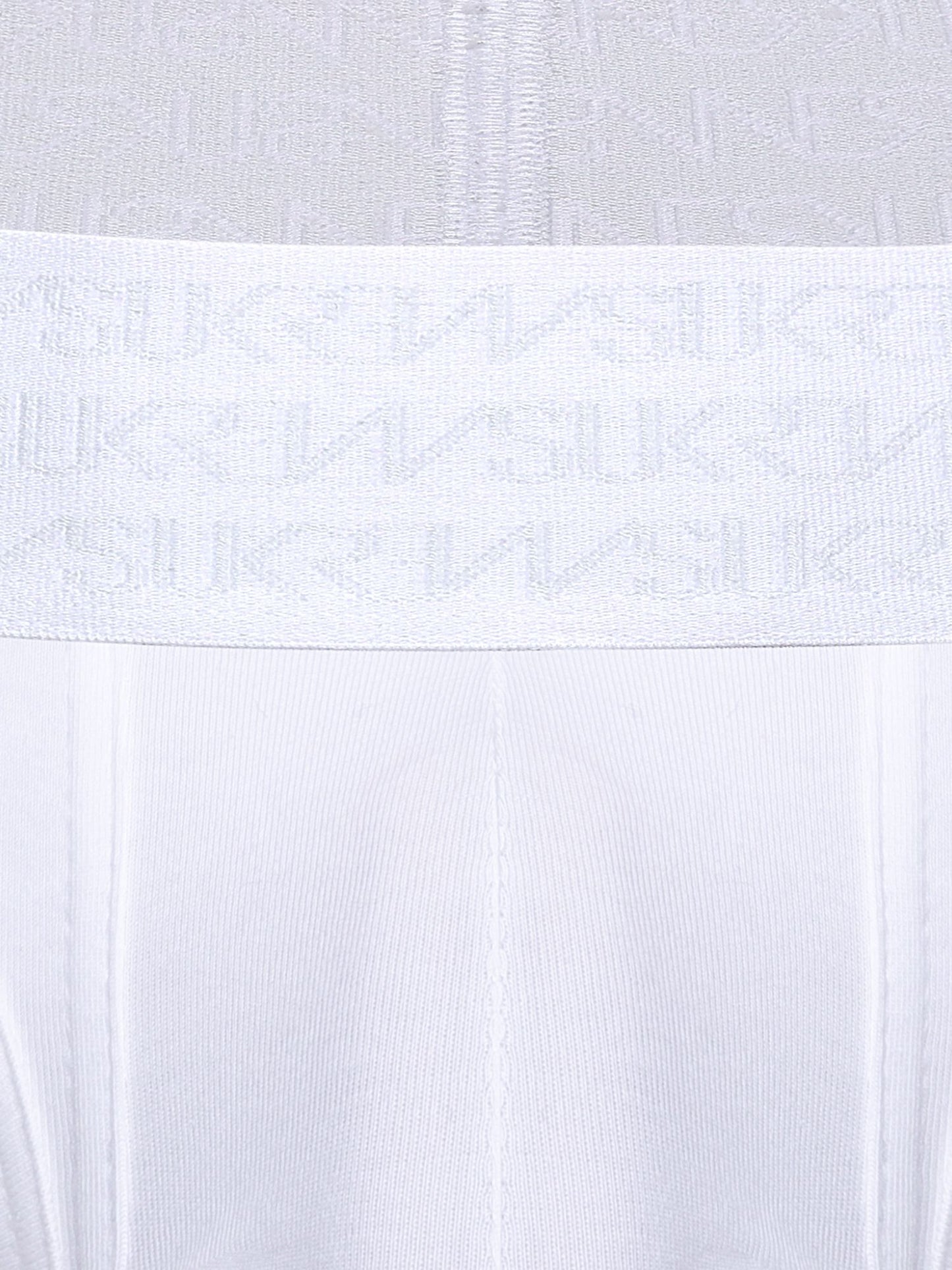 Close-up of a white underwear or garment waistband with a repeating tonal SUKREW logo pattern, shown against matching white fabric.