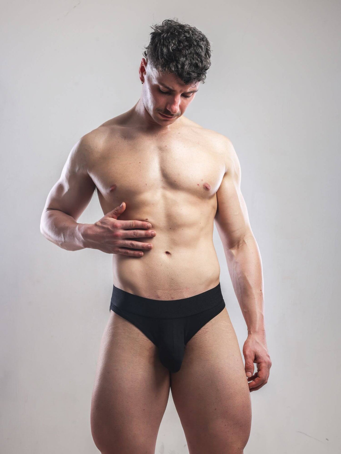 Man wearing black underwear against a plain background