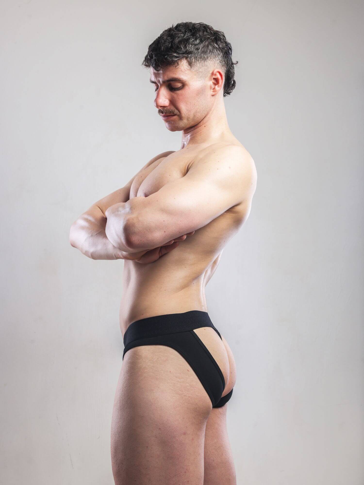 Man wearing black underwear against a plain background