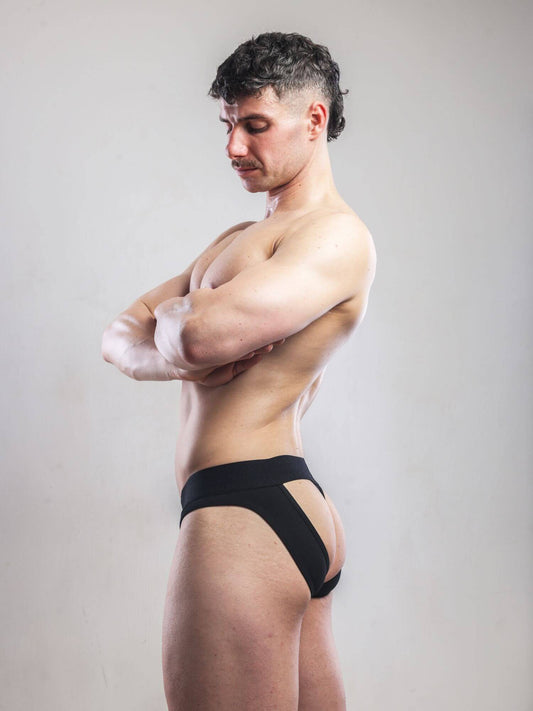 Man wearing black underwear against a plain background