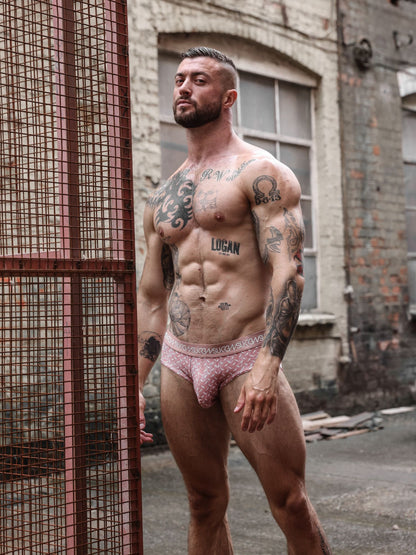 A muscular, tattooed man wearing red patterned briefs. The underwear has a visible waistband with the brand name printed on it.