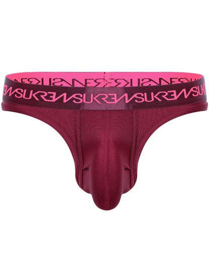 A men's thong in deep burgundy with a bright pink elastic waistband featuring the brand name 'SUKREW' repeated in black.