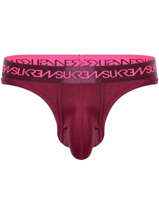 A men's thong in deep burgundy with a bright pink elastic waistband featuring the brand name 'SUKREW' repeated in black.