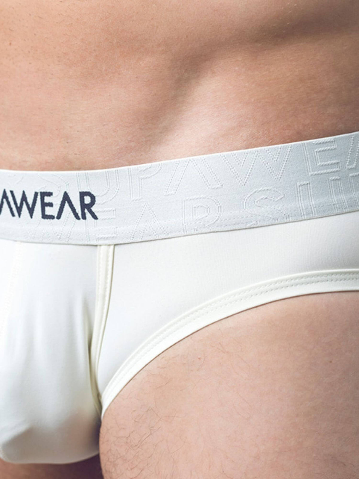 Close-up of a person wearing white underwear with a wide waistband featuring the brand name 'SUPAWEAR' in dark navy text.