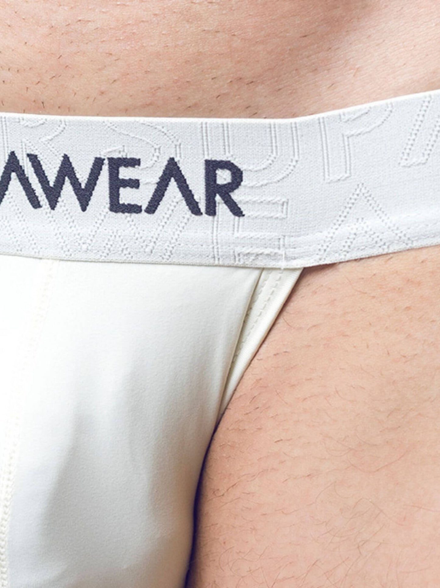 Close-up of a person wearing white underwear with a white waistband featuring the dark navy SUPAWEAR logo.